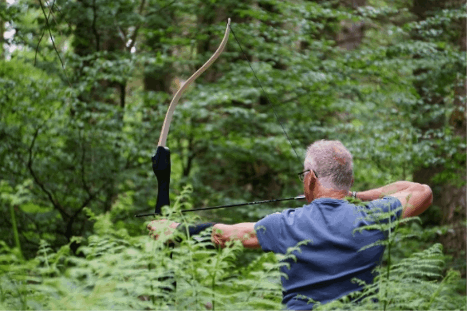 Mann zielt mit Pfeil und Bogen im Wald
