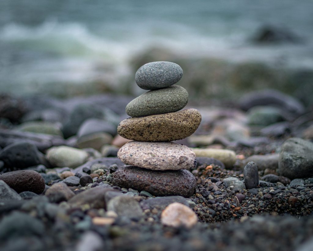 Ein ruhiger Stapel aus ausbalancierten Steinen vor dem Hintergrund des Meeres, der Harmonie und Ausgewogenheit symbolisiert.